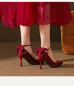 Elegante rote Seiden-Stilettos mit spitzer Kappe, Fesselriemen und Schleife.