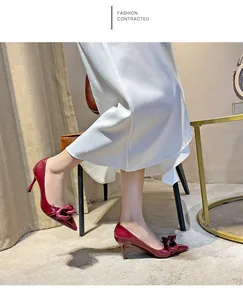 Elegant burgundy patent leather pointed toe stiletto heels with decorative knot detail.