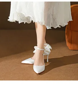 Detailansicht eleganter weißer Seiden-Pumps mit Knöchelriemen und großer Schleife an der Ferse