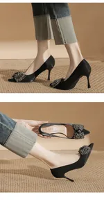Close-up of black pointed-toe stiletto heels featuring a sparkling crystal bow decoration.