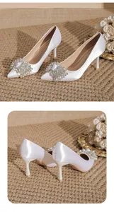 Detailed view of white satin pointed-toe pumps with crystal brooch embellishment
