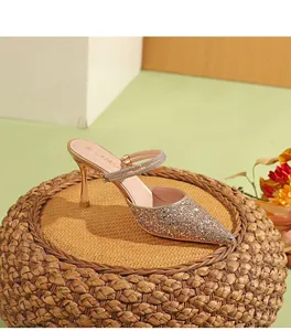 Vista laterale di eleganti sabot a spillo glitter champagne su uno sgabello di paglia