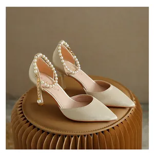 Detailansicht eleganter champagnerfarbener Stilettos mit schicken Perlen-Fesselriemen