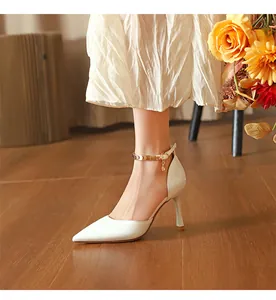 Seitenansicht weißer Stöckelschuhe mit spitzer Zehenpartie und goldenem Knöchelriemen