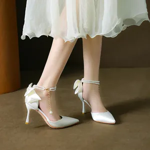 Elegant white satin pointed toe stilettos featuring pearl ankle strap and silk bow heel.