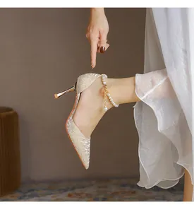 Side view of elegant beige pointed toe stiletto pumps with a pearl anklet detail.