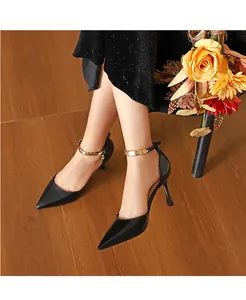 Nahaufnahme von schwarzen spitzen Stilettos mit goldenen Metall-Fesselriemen am Modell