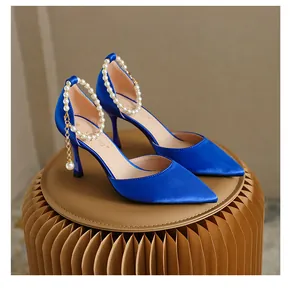 Detailansicht der königsblauen Satin-Pumps mit eleganten Perlen-Knöchelriemen und Anhänger