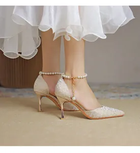 Detailed view of pointed-toe pumps with elegant pearl ankle straps and textured champagne fabric.