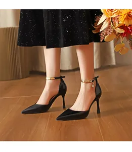 Elegante schwarze Stilettos mit spitzer Kappe und goldener Fesselriemchen-Verzierung.