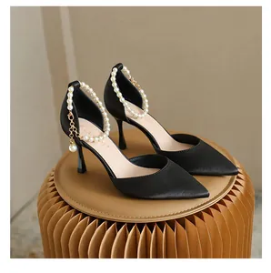 Detailansicht der eleganten schwarzen Stiletto-Pumps mit Perlen-Fesselriemen und spitzer Kappe.