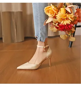 Detailed macro view of beige crocodile embossed pointed-toe high heels with ankle strap