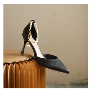 Detailansicht eleganter schwarzer Pumps mit spitzer Zehenpartie und Perlen-Fußkette.