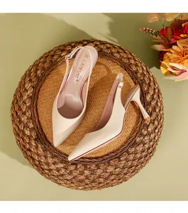 Κομψές μπεζ μυτερές γόβες slingback τοποθετημένες σε ρουστίκ υφαντό ψάθινο χαλάκι