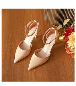 Elegante nudefarbene High Heels mit spitzer Zehenpartie und Knöchelriemen auf Holz