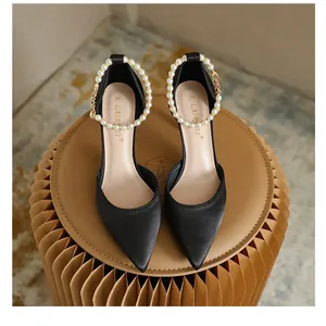Draufsicht auf schwarze spitze Satin-High-Heels mit dekorativen Perlen-Knöchelriemen