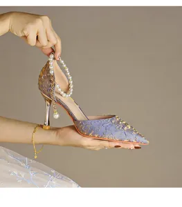 Close-up of elegant pointed-toe high heel with decorative pearl strap and metallic texture