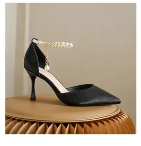Detailansicht der schwarzen spitzen Stilettos mit elegantem Perlen-Knöchelriemen