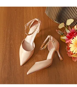 Elegante beige spitze High Heels mit goldener Kette am Knöchelriemen in der Draufsicht.