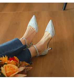 Primer plano de elegantes tacones de aguja plateados con purpurina y tiras al tobillo.