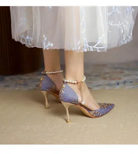 Close-up of purple pointed stiletto pumps with gold embroidery and pearl ankle strap.