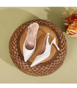 Κομψές λευκές μυτερές γόβες slingback τοποθετημένες σε ρουστίκ φόντο από πλεκτή ψάθα