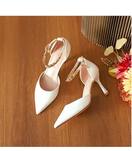 Elegante weiße spitze High Heels mit goldenen Knöchelriemen auf Holzgrundlage.