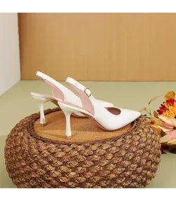 Πλαϊνή όψη από κομψές λευκές γόβες slingback με μυτερή μύτη σε υφαντό σκαμπό