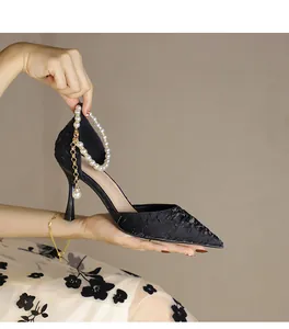 Close-up detail of black lace pointed-toe high heels with elegant pearl ankle strap decoration