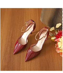 Elegante Detailansicht von burgunderroten Lackleder-Pumps mit goldener Kette am Knöchelriemen