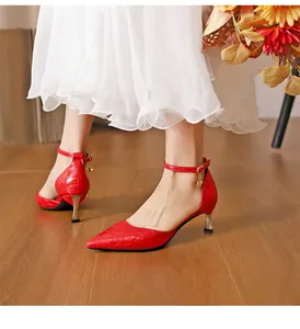 Detailed view of elegant red crocodile pattern pointed-toe stiletto heels with ankle straps.
