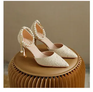 Detailed view of elegant beige stiletto pumps with pearl ankle strap and textured fabric