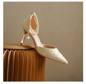 Side profile detail of elegant cream pointed stiletto pump with pearl ankle strap