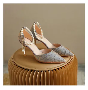 Detailed view of blue textured pointed-toe high heels with elegant pearl ankle straps