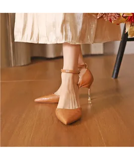Detailed view of elegant brown croc-patterned pointed-toe pumps with ankle strap on model