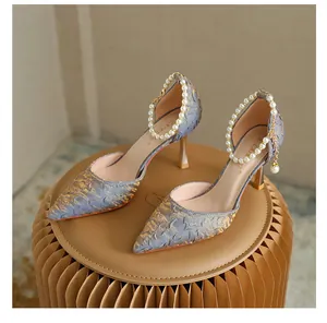 Detail view of blue and gold pointed high heels with elegant pearl ankle straps.