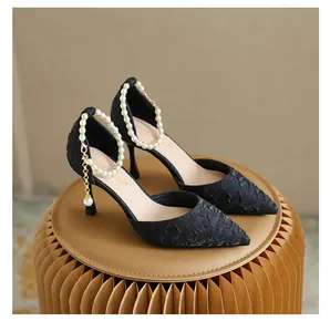 Detail view of elegant black pointed toe high heels with pearl ankle strap decoration