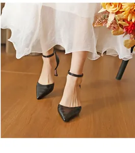 Elegant black crocodile pattern pointed-toe high heels with ankle straps on feet