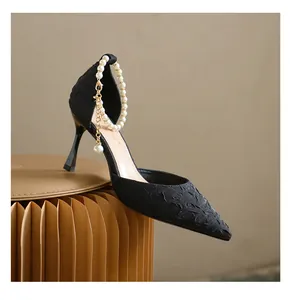 Close-up of elegant black pointed toe stiletto heels featuring a pearl ankle strap detail