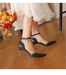 Close-up of black crocodile-textured pointed-toe high heels with ankle straps