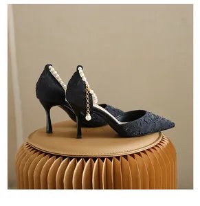 Detail of black jacquard pointed-toe stiletto heels with elegant pearl ankle strap