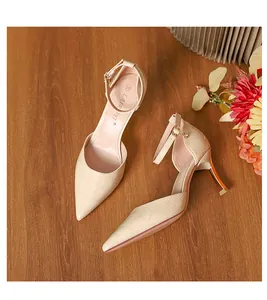 Elegant beige crocodile-embossed pointed-toe pumps with ankle straps in a detail view.