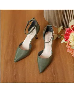 Close-up of green crocodile embossed pointed-toe high heels with ankle straps.