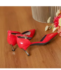 Detailed view of red crocodile-embossed pointed-toe high heels with crystal charms.