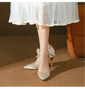 Nahaufnahme champagnerfarbener Satin-Heels mit Fesselriemen und großem Schleifendetail.