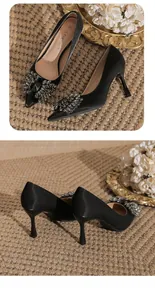 Elegant black pointed-toe stiletto pumps featuring luxury rhinestone bow detailing