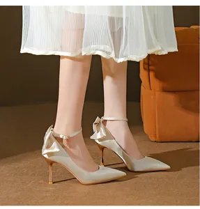 Nahaufnahme eleganter champagnerfarbener Satinpumps mit Schleife und Fesselriemen