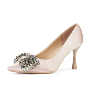 Side view of luxury champagne satin pointed toe pump with crystal bow detail