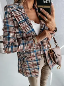 Dettaglio di un blazer a quadri marrone e blu con bottoni dorati di tendenza.