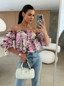 Vue détaillée d'une blouse à fleurs avec manches bouffantes et un jean bleu clair.